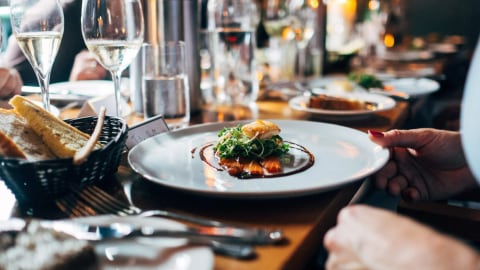 An elegant private fine dining table set with plated dishes and wine