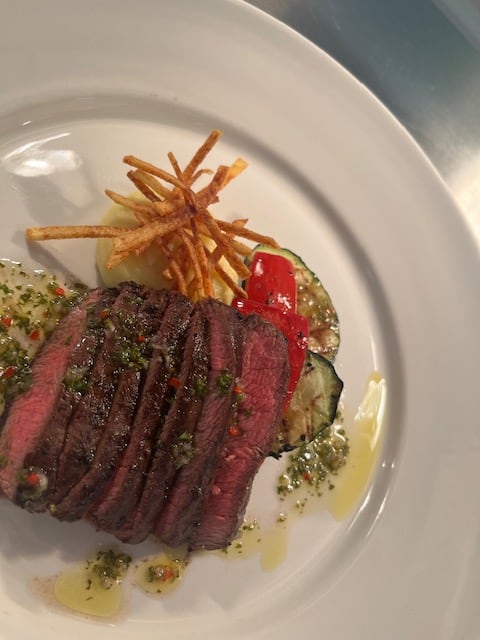 Sliced steak served with vegetables and crisp potato