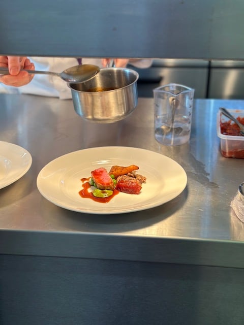 A chef finishing a plated course at the pass