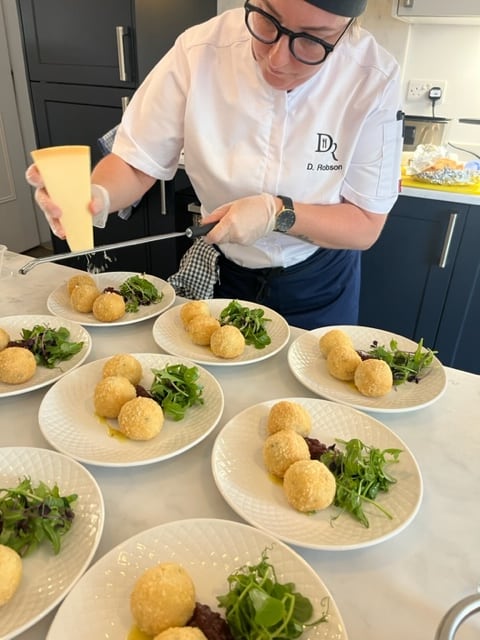 Debbie finishing a plated course with crisp croquettes and greens